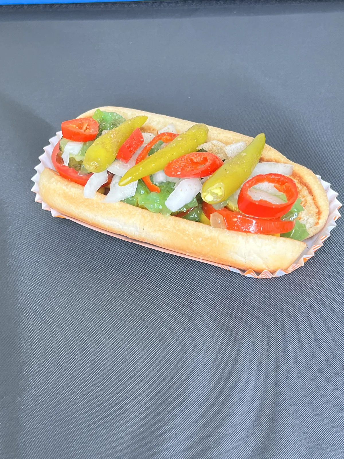 Signature dog topped with peppers, tomato, and onion